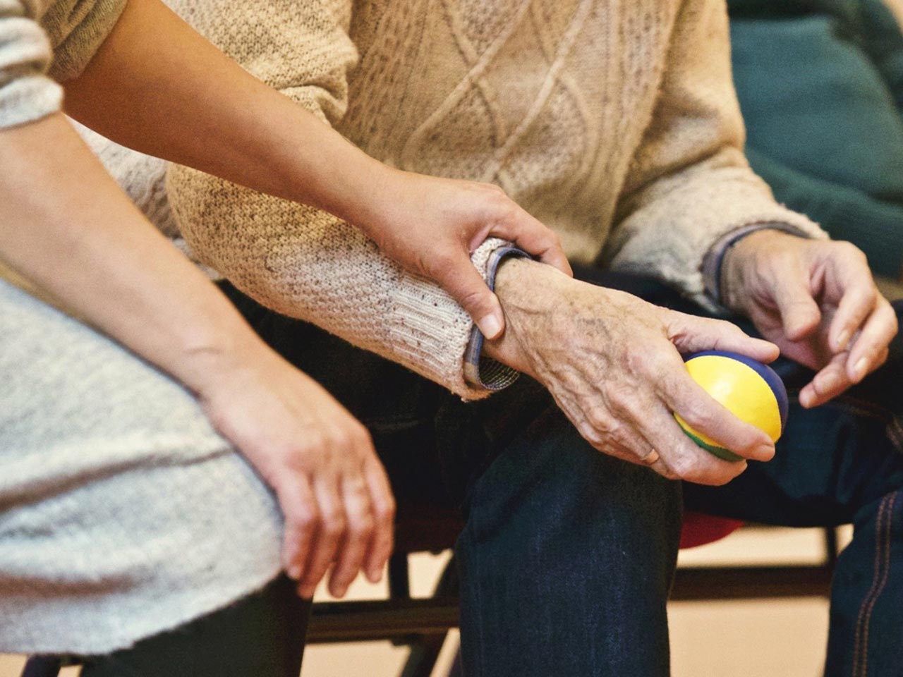 Zwei Personen, eine hält die Hand der anderen, gelber Ball in der Hand.